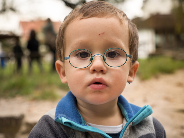 Junge mit Brille guckt im Objektiv